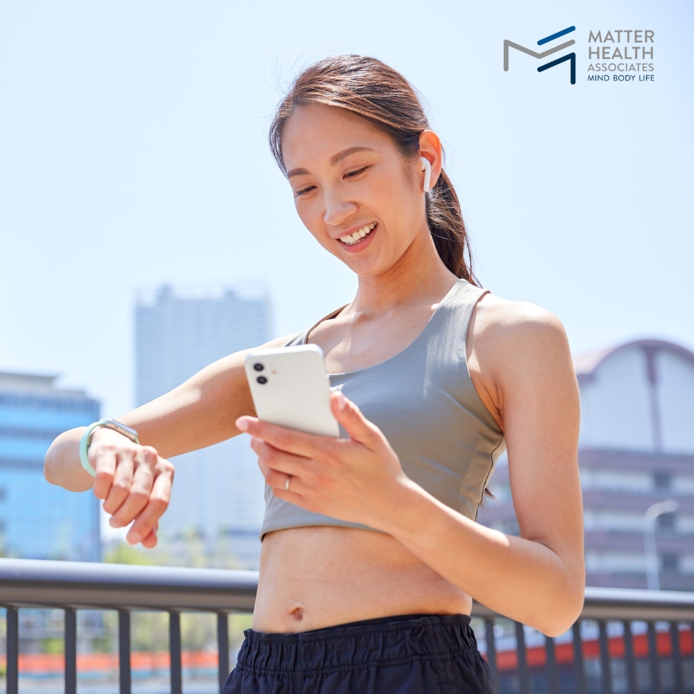 How to Understand the Good and Bad of Exercise and Nutrition Technology | Person using fitness tracking app on smartphone while taking a break during an outdoor workout, representing the blend of technology and mindful exercise habits.