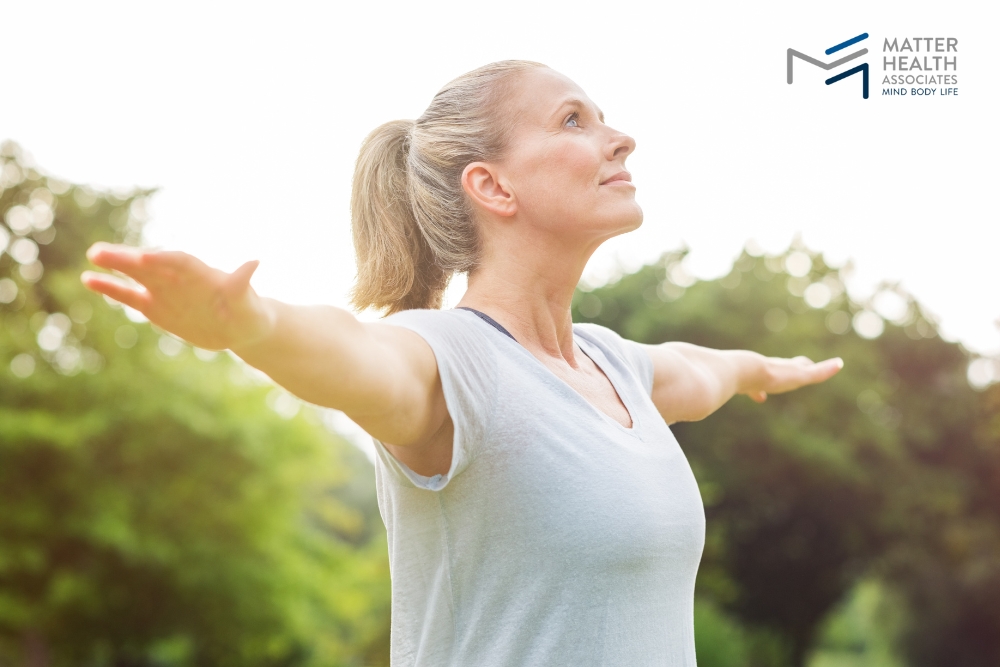 Why Exercising for Aging Gracefully Matters More Than Looks | A smiling woman doing yoga in the park, representing the shift from exercising for appearance to exercising for health, mobility, and aging well.