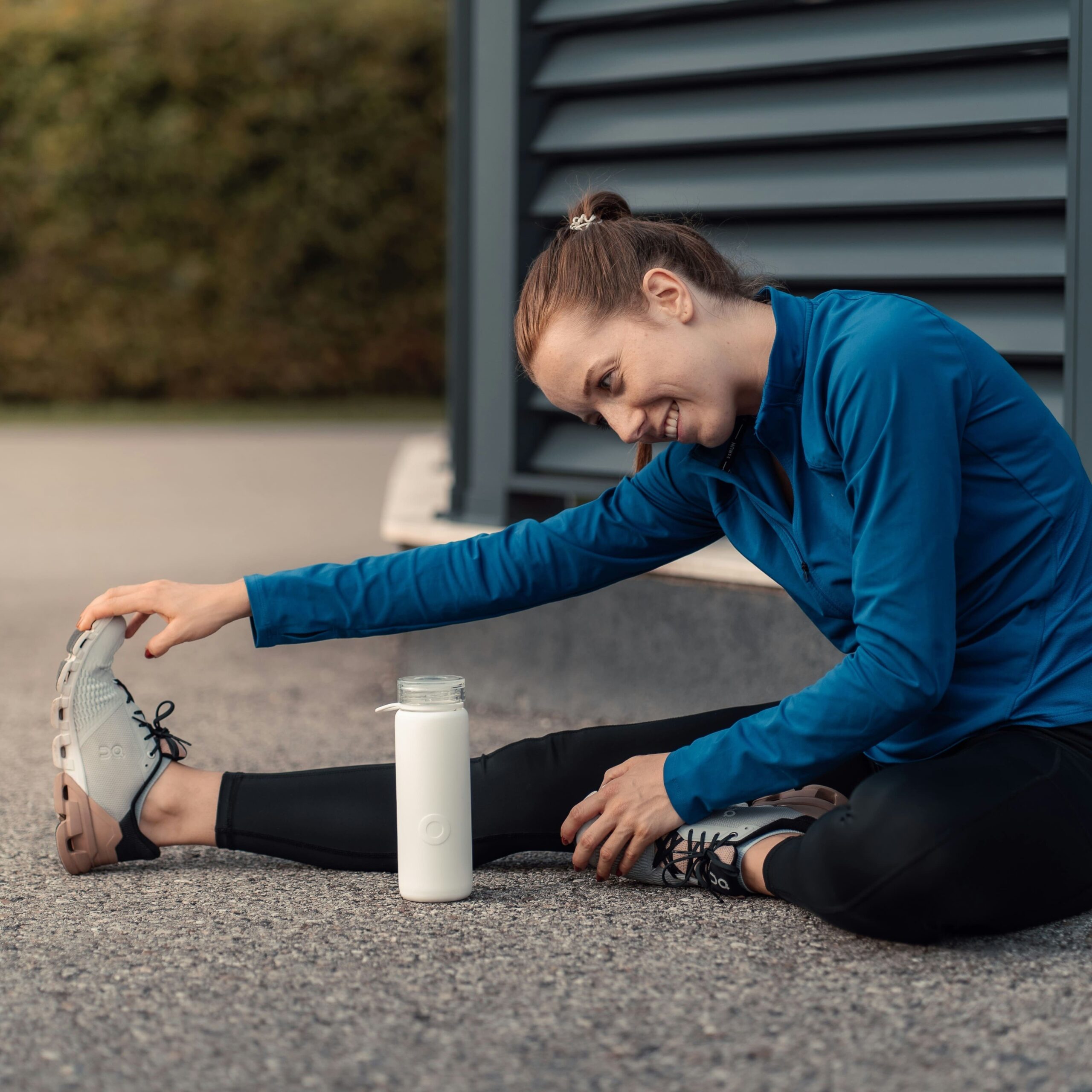 Young woman happily stretching outdoors as part of an effective exercise program guided by personal training