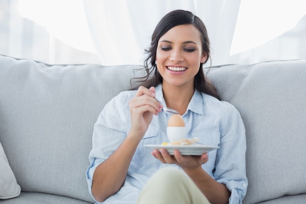 Woman eating a hard-boiled egg as part of building sustainable health and wellness habits through small daily changes