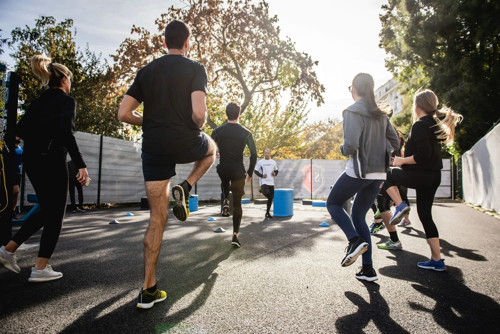Group of adults doing light outdoor exercises as part of an effective exercise program and personal training routine.