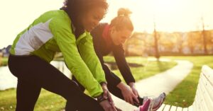 Two women stretching outdoors as part of healthy lifestyle and wellness habits
