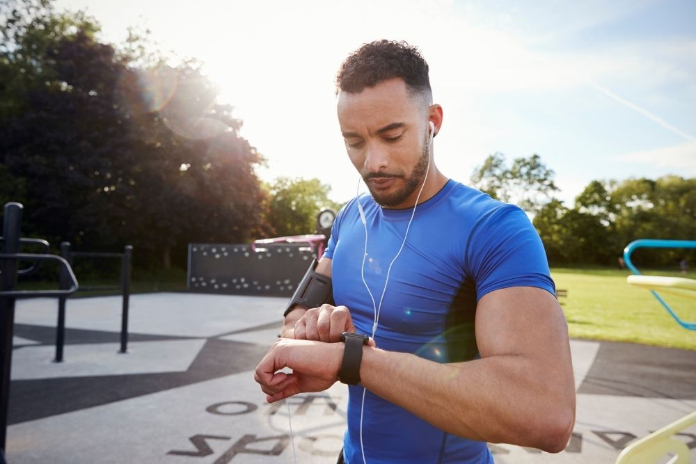A man running outdoors and checking his health app
