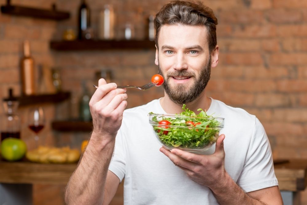 Man eating a healthy salad and learning how to boost his metabolism naturally