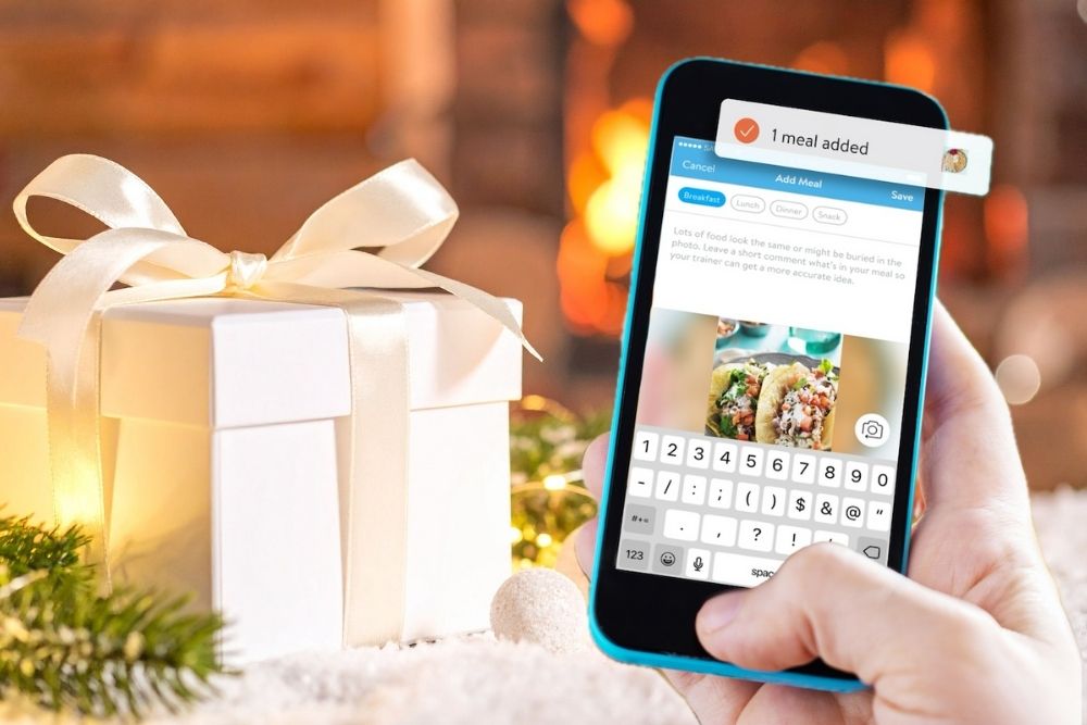 A hand holding a phone that shows the Matter Health Associates App interface. A Christmas gift on the background.