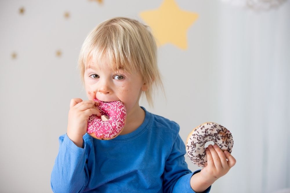 A child eating donuts, highlighting the importance of managing early exposure to prevent lifelong sugar addiction.