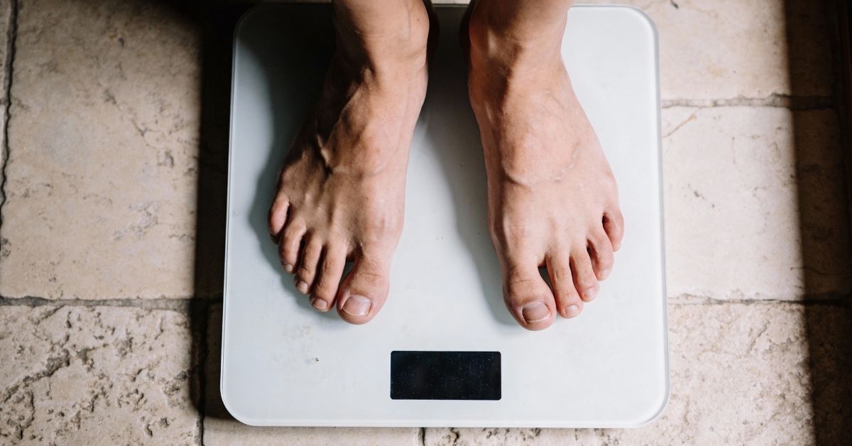 Feet on a digital scale representing the common obsession with numbers in health and nutrition.
