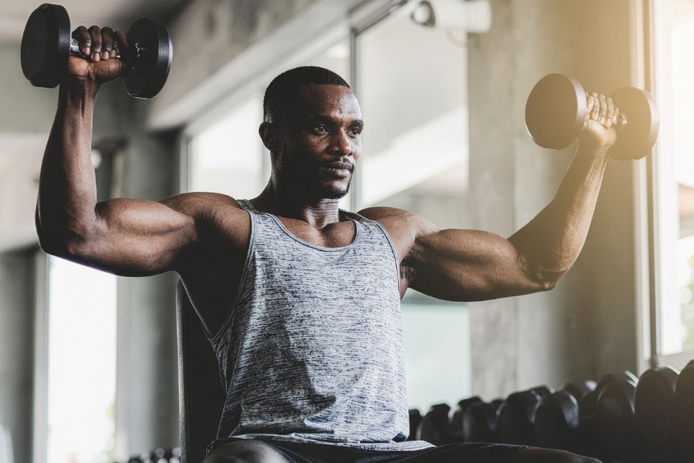 A man using dumbbells with perfect form to prioritize movement quality over numbers in health and nutrition.