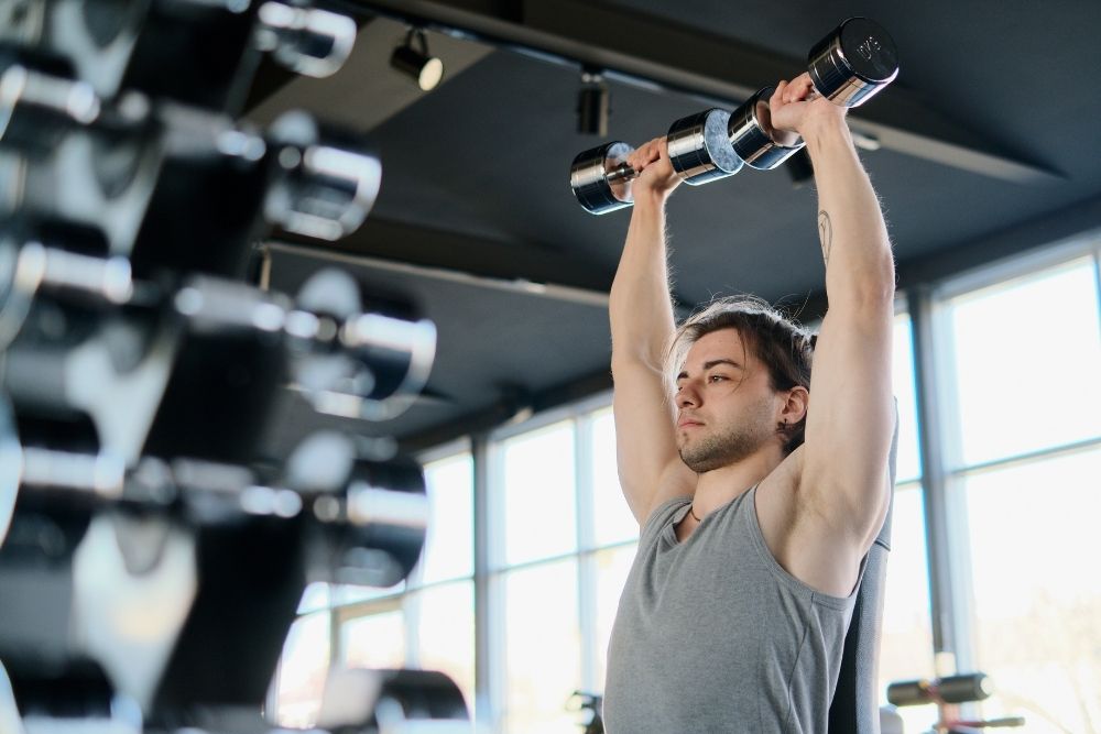 A man performing a dumbbell workout to build a natural strength baseline without relying on creatine.