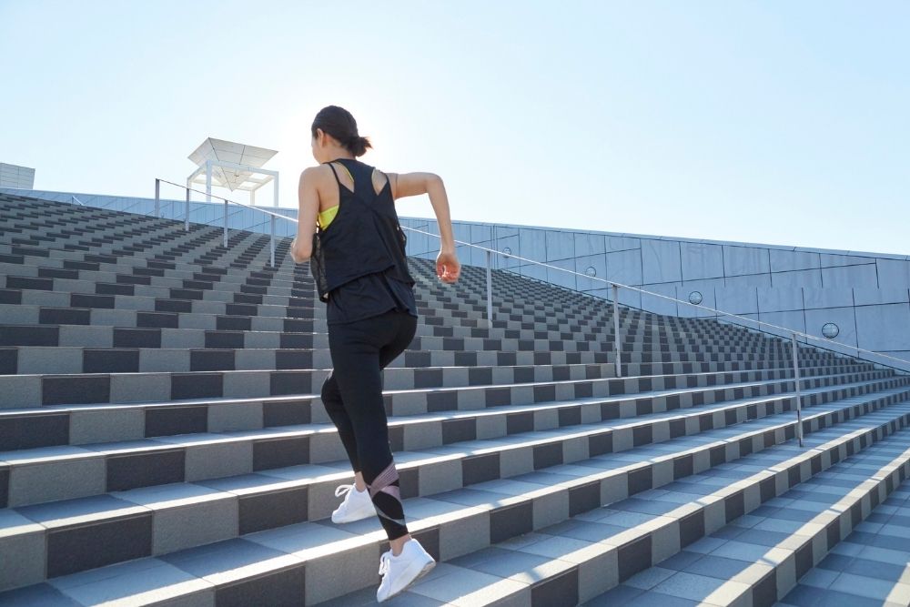 A woman climbing stairs, symbolizing the courage to take small, incremental steps when you start your fitness journey.