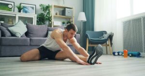 A man stretching in his living room as he prepares to start his fitness journey with simple, accessible movements.