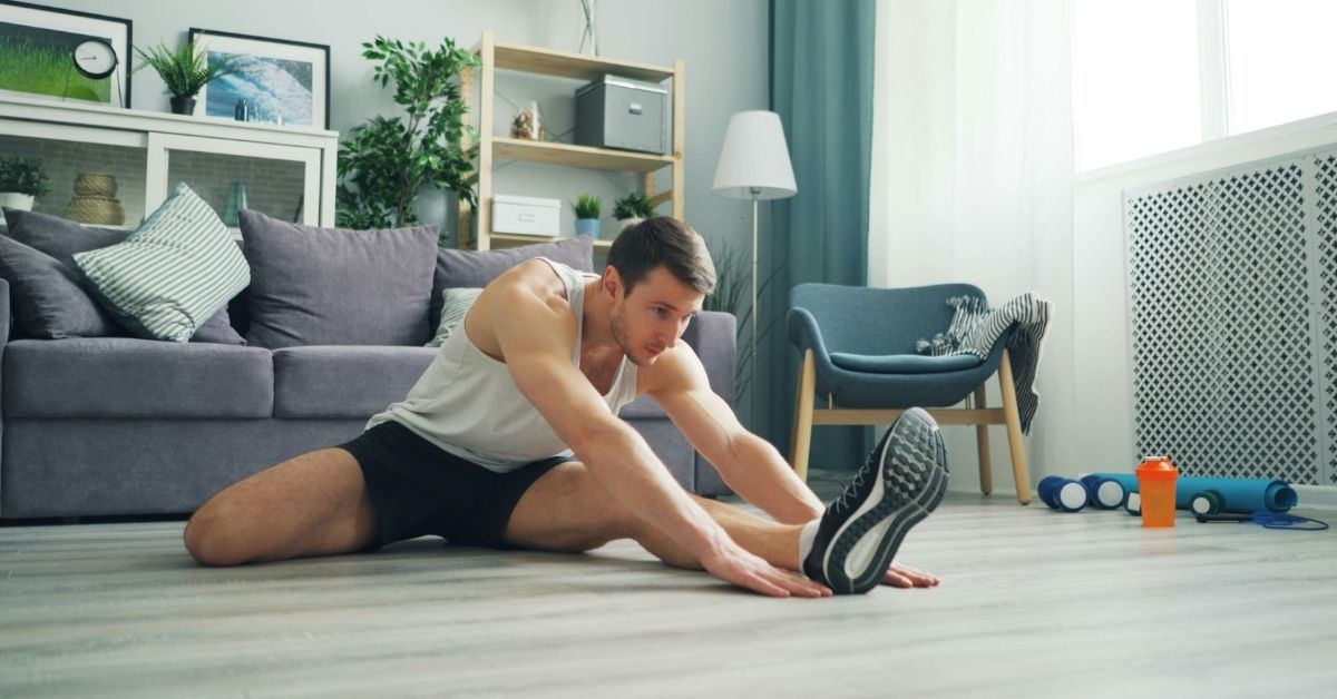 A man stretching in his living room as he prepares to start his fitness journey with simple, accessible movements.