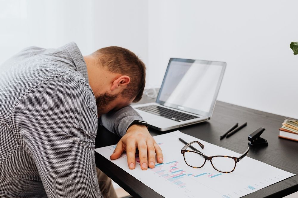 A man experiencing fatigue at work, a common side effect of how sugar addiction provides "fake energy" followed by a crash.
