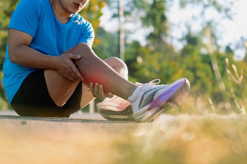 A runner pausing due to leg discomfort, illustrating why identifying the root cause is essential for returning to pain-free exercise.