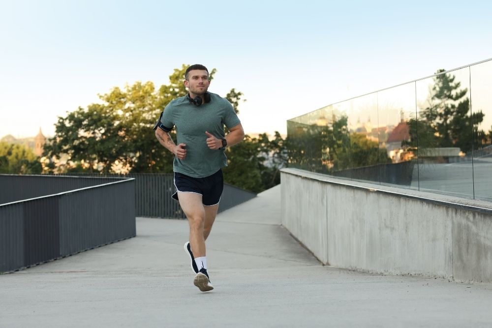 A healthy man running outdoors with proper form, achieving his goal of consistent and pain-free exercise.