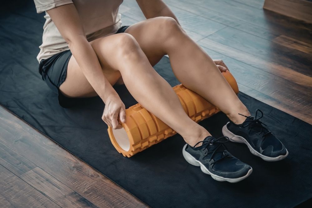 Close-up of an athlete using a foam roller for muscle recovery to manage delayed onset muscle soreness.