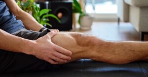 Close-up of a man massaging his leg to alleviate muscle soreness after a training session.