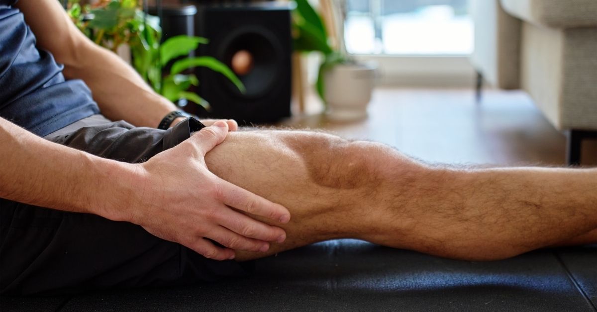 Close-up of a man massaging his leg to alleviate muscle soreness after a training session.