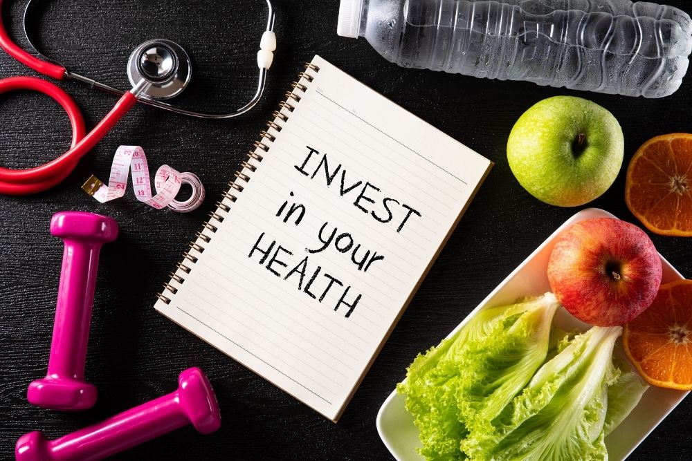 A notebook with "Invest in your health" text next to healthy food