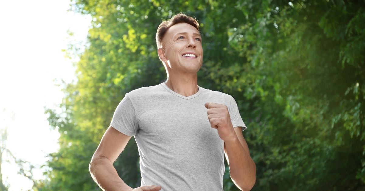 A middle aged man jogging while smiling, showcasing active aging.