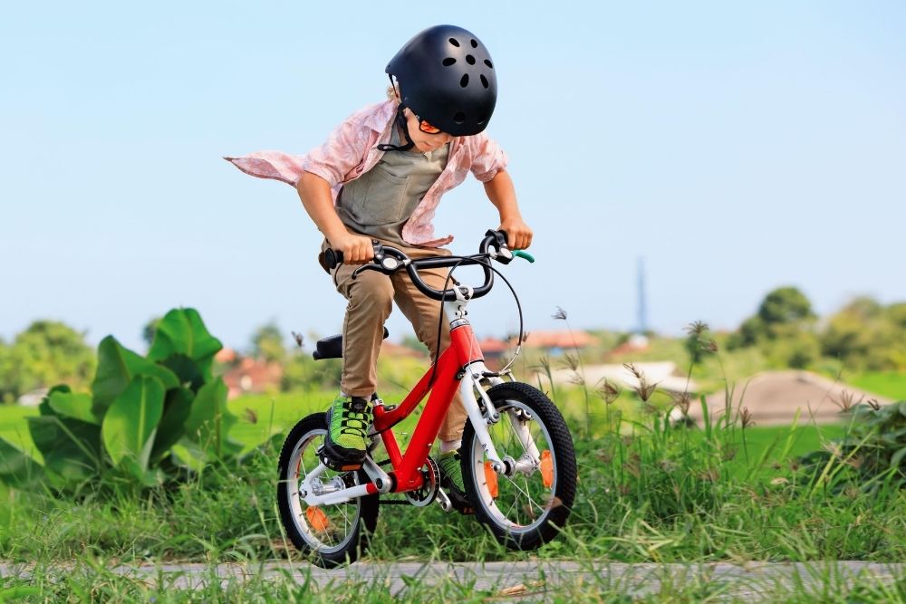 A young child wearing a helmet and riding a bicycle outdoors, highlighting natural outdoor activity for kids and teens fitness.