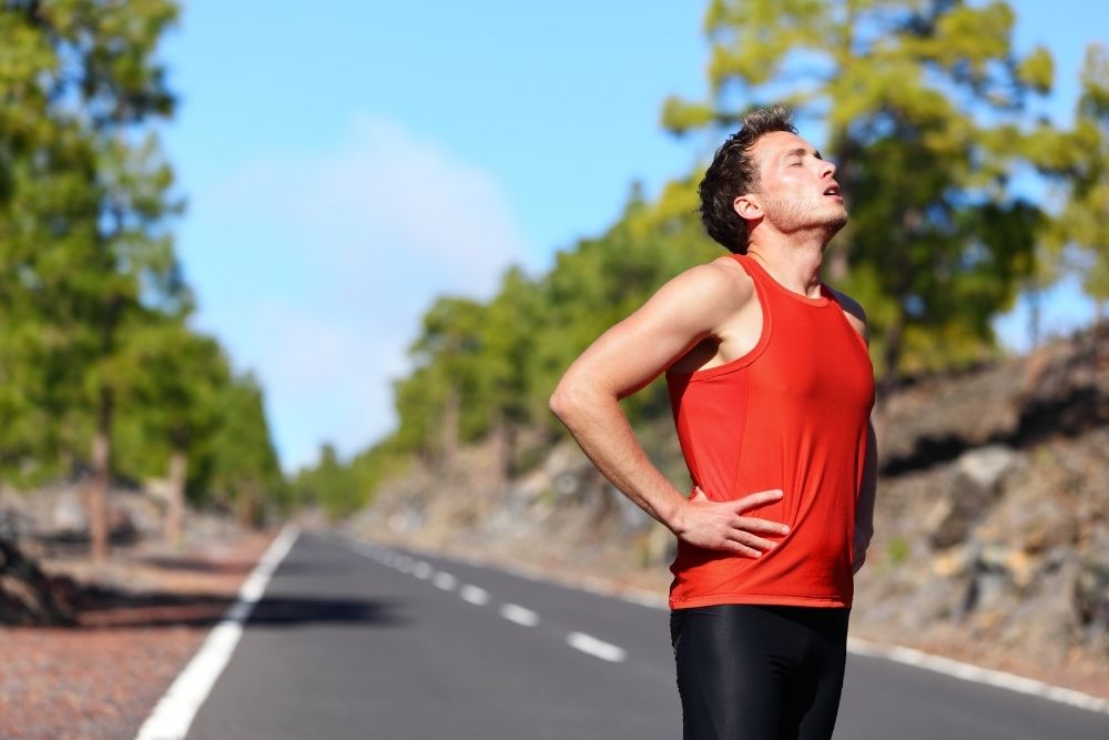 An exhausted athlete resting during a workout, illustrating why energy levels can dip during hot summer months like August.