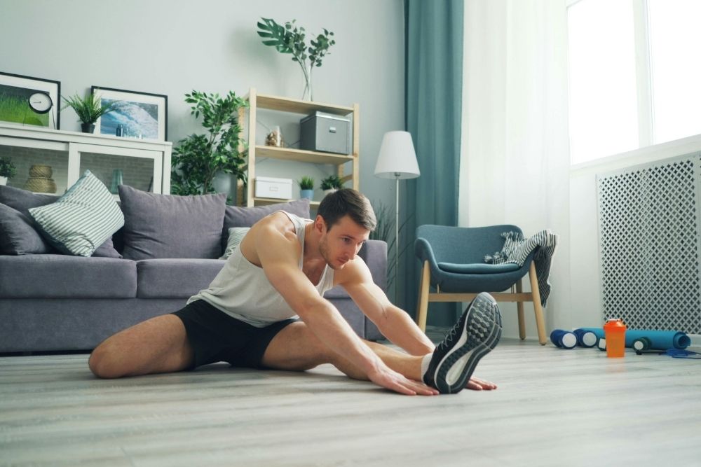 An athlete focusing on stretching and recovery indoors, symbolizing the body's internal adaptation processes.